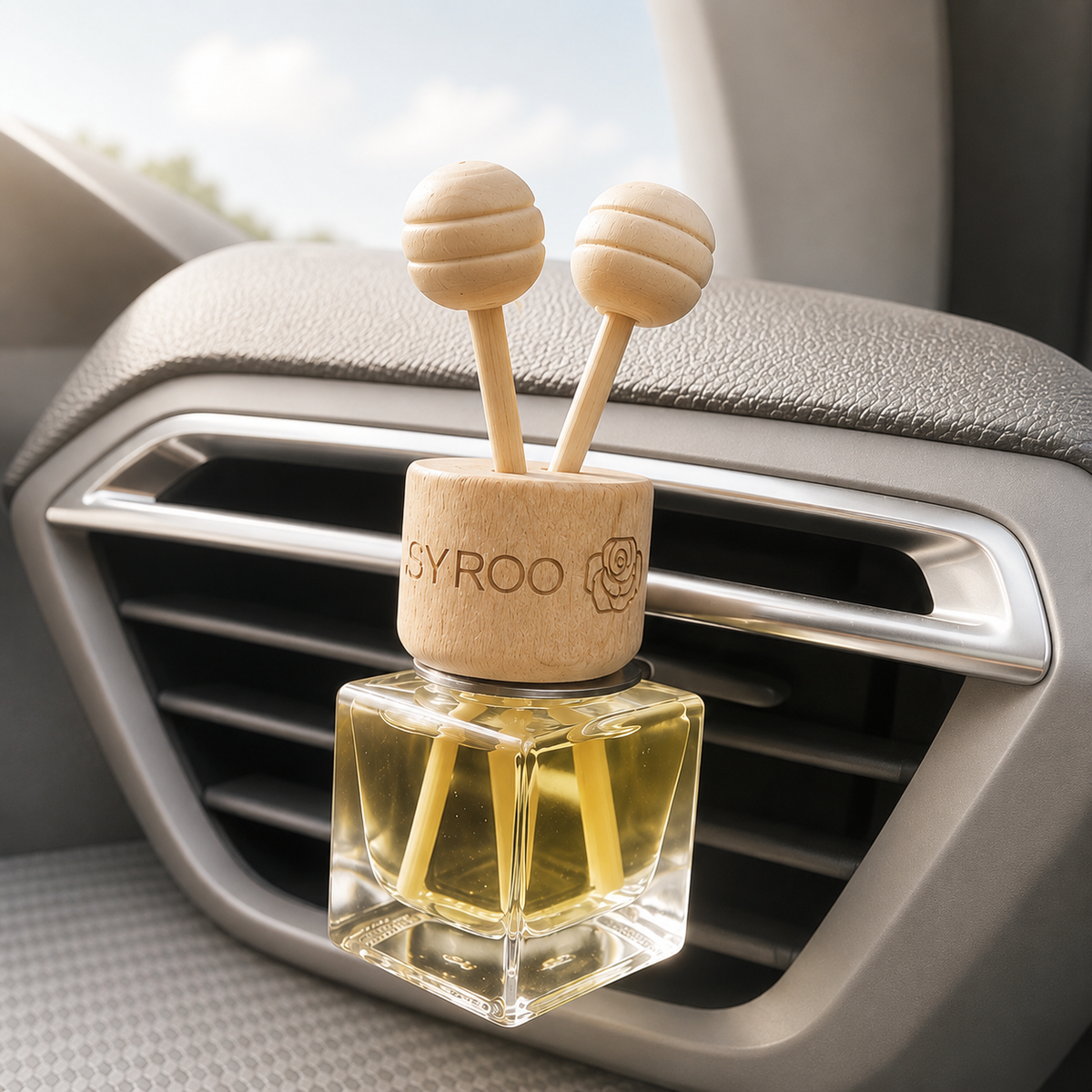 Citrus car diffuser clipped to a dashboard air vent, with golden oil in a square glass bottle, a wooden cap and two round-tipped reeds.