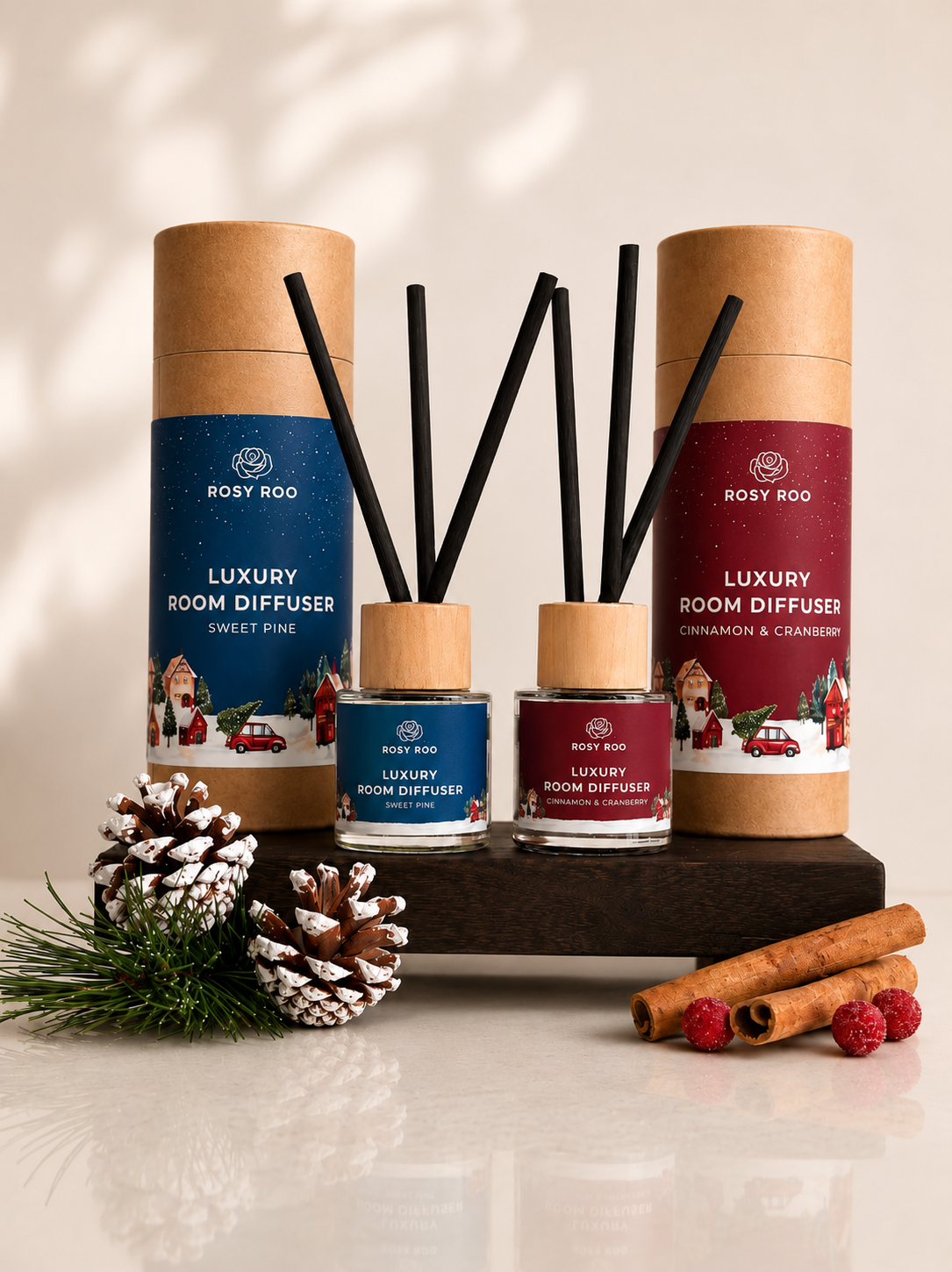 Two Rosy Roo luxury room diffusers in sweet pine and cinnamon-cranberry scents, styled with pinecones, greenery, cinnamon sticks, and berries.